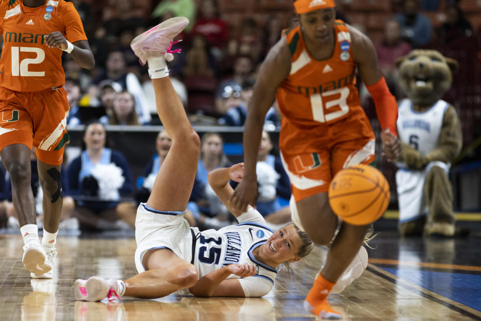 Villanova's Brooke Mullin (15) falls to the court as Miami's Lashae Dwyer (13) dribbles the ball to the basket in the second half of a Sweet 16 college basketball game at the NCAA Tournament in Greenville, S.C., Friday, March 24, 2023. (AP Photo/Mic Smith)