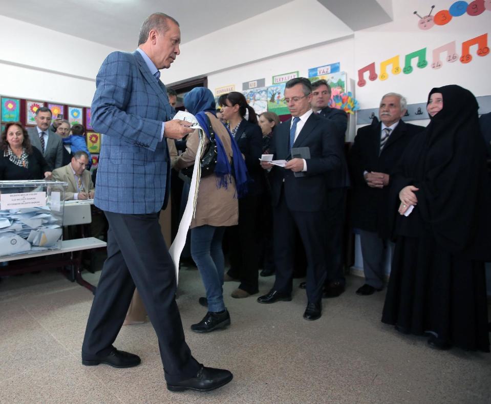 Turkey's Prime Minister Recep Tayyip Erdogan walks with his ballot papers in hand at a polling station in Istanbul, Turkey, Sunday, March 30, 2014. Erdogan has a central role in Turkey's local elections Sunday even though his name won't be on the ballots. The elections are widely seen as a referendum on Erdogan's tumultuous rule of more than a decade, and the prime minister has been campaigning as if his own career were on the line. High-profile races for mayor of Istanbul and Ankara with incumbents from Erdogan's Justice or Development Party, better known by its Turkish acronym AKP, will be watched closely for signs of whether his influence is waning. The Turkish elections board says more than 50 million people are eligible to vote. (AP Photo/Emrah Gurel)