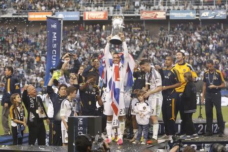 Los Angeles Galaxy's David Beckham holds the trophy after the Galaxy defeated the Houston Dynamo to win the MLS Cup championship soccer game in Carson, California, December 1, 2012. REUTERS/Danny Moloshok