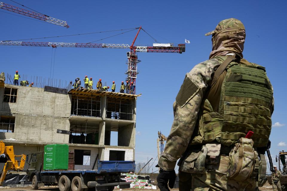 FILE - A Russian soldier guards the site of a new apartment building which is is being built with the support of the Russian Defense Ministry, in Mariupol, on the territory which is under the Government of the Donetsk People's Republic control, eastern Ukraine, on July 13, 2022. According to Russian state TV, the future of the Ukrainian regions occupied by Moscow's forces is all but decided: Referendums on becoming part of Russia will soon take place there, and the joyful residents who were abandoned by Kyiv will be able to prosper in peace. In reality, the Kremlin appears to be in no rush to seal the deal on Ukraine's southern regions of Kherson and Zaporizhzhia and the eastern provinces of Donetsk and Luhansk. (AP Photo)
