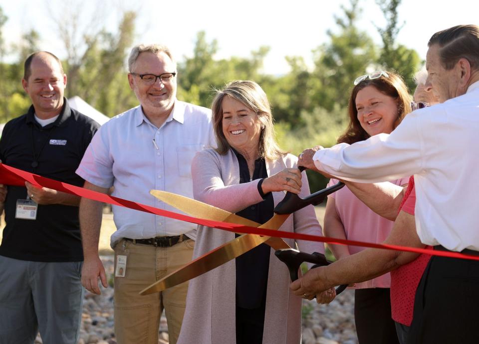 West Valley Mayor Karen Lang, center, and others participate in a ribbon-cutting at Pioneer Crossing Regional Park in West Valley on Thursday.