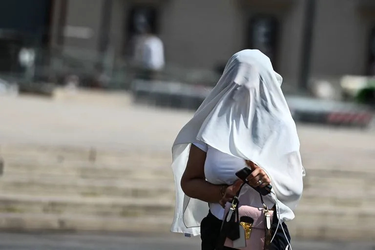 Una mujer se protege del sol con un pareo blanco en Mil&#xe1;n, en medio de la ola de calor que afecta a toda Italia