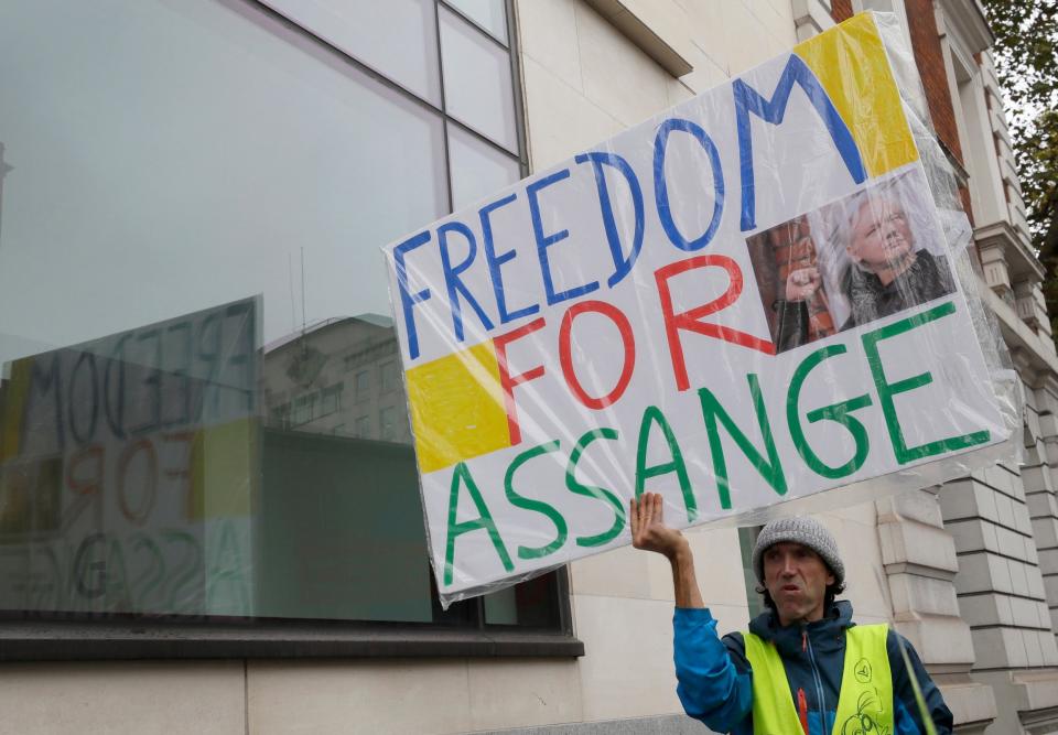 A man stands outside court with a sign saying 'freedom for Assange' (AP)