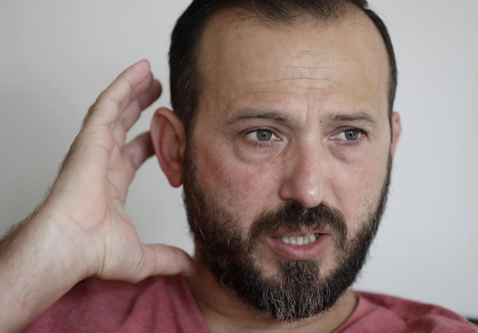 In this Tuesday, Feb. 25, 2020, photo, Al Noor mosque shooting survivor Temel Atacocugu gestures during an interview at his home in Christchurch, New Zealand. When the gunman walked into the mosque, Atacocugu was kneeling for Friday prayers. He looked up into the man's face, thinking he was a police officer because of his paramilitary outfit. Time slowed. Temel saw a puff of smoke come from the raised gun, felt a bullet smash into his teeth, and thought: "Oh, my God, I'm dying." (AP Photo/Mark Baker)