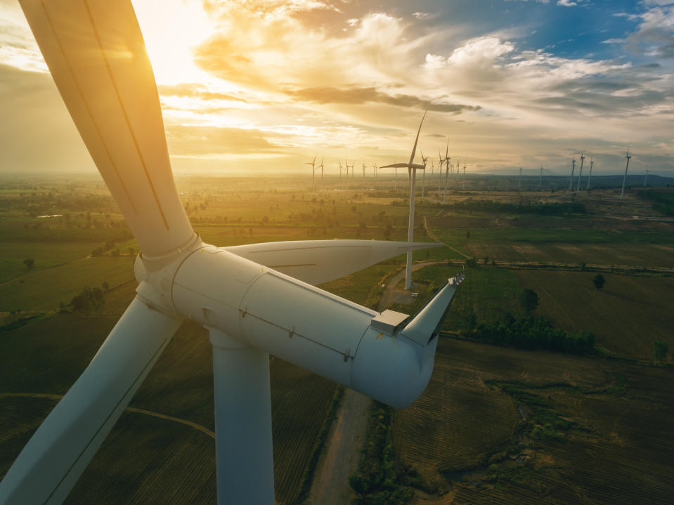 A wind turbine with the sun shining brightly.