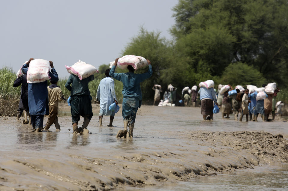 Victims of unprecedented flooding from monsoon rains receive relief aid organized by the Edhi Foundation, in Ghotki District of Sindh Pakistan, Wednesday, Sept. 7, 2022. (AP Photo/Fareed Khan)