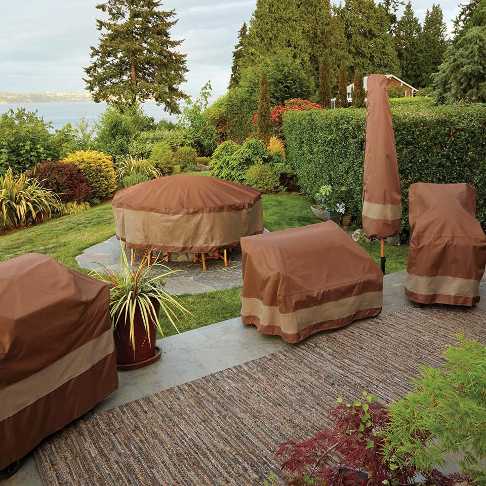 Outdoor patio tables, sofas, grill, chair, and umbrella protected by brown covers