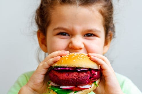 <span class="caption">There's more behind that vegan burger than it seems.</span> <span class="attribution"><a class="link " href="https://www.shutterstock.com/image-photo/happy-hungry-child-girl-eating-healthy-585528380?src=a78c5a5f-ea93-43b0-9eb7-51cf480c13e2-1-41" rel="nofollow noopener" target="_blank" data-ylk="slk:Nina Firsova/Shutterstock.com;elm:context_link;itc:0;sec:content-canvas">Nina Firsova/Shutterstock.com</a></span>