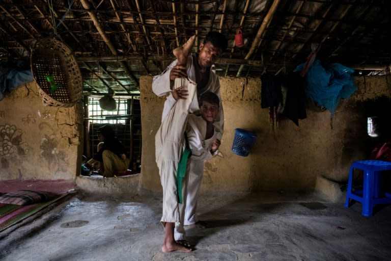 Rohingya refugee Mohammad Selim (top) trains his daughter Nasima Akhtar, 8, in taekwondo inside their tent at the Kutupalong camp near Cox's Bazar, Bangladesh