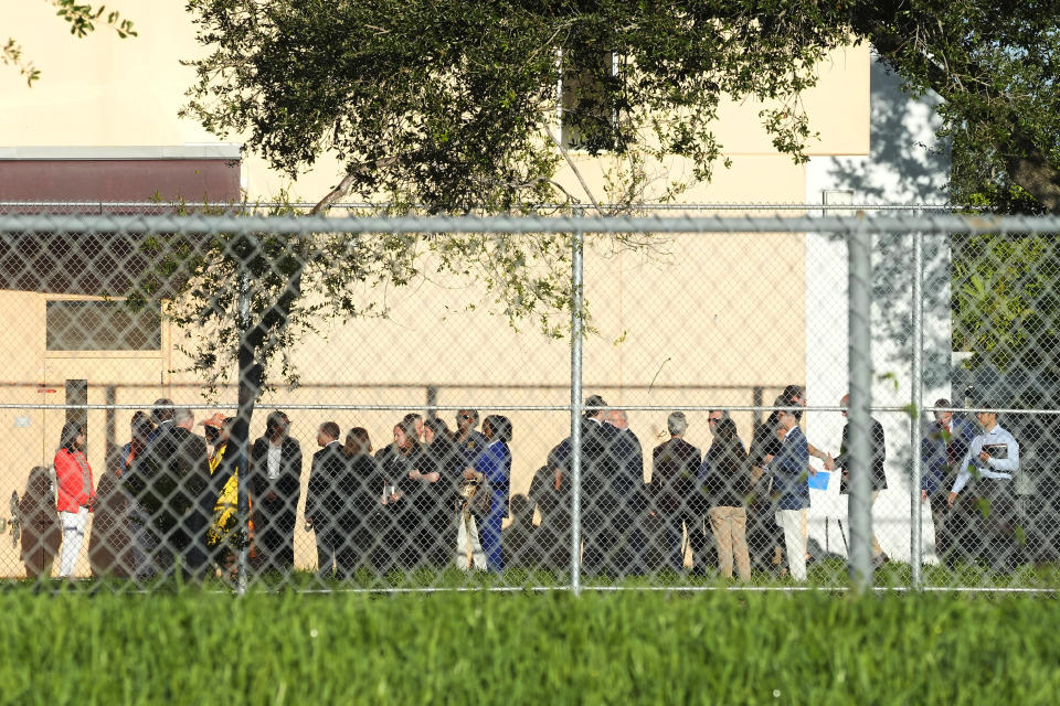 Nine members of Congress and others wait to enter Marjory Stoneman Douglas High School, Friday, Aug. 4, 2023, in Parkland, Fla. The group will tour the blood-stained and bullet-pocked halls, shortly before ballistics technicians reenact the massacre that left 14 students and three staff members dead in 2018. The reenactment is part of a lawsuit filed by the victims' families against former Deputy Scot Peterson and the Broward Sheriff's Office. (AP Photo/Marta Lavandier)