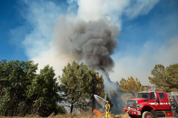 Smoke from a wildfire rises above a firefighter as he tries to stop the blaze from crossing Loma Prieta Ave. near Morgan Hill, Calif., on Tuesday, Sept. 27, 2016. (Photo: Noah Berger/AP)