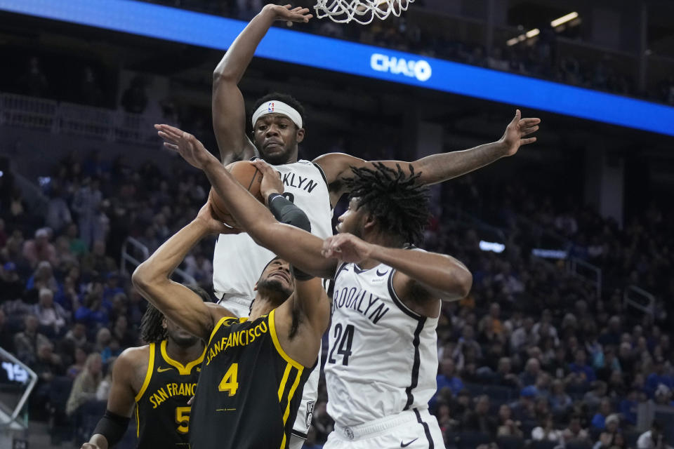 Golden State Warriors guard Moses Moody (4) shoots against Brooklyn Nets center Day'Ron Sharpe, top, and guard Cam Thomas (24) during the first half of an NBA basketball game in San Francisco, Saturday, Dec. 16, 2023. (AP Photo/Jeff Chiu)