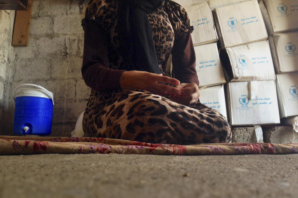 FILE - In this file photo taken Wednesday, Oct. 8, 2014, a 15-year-old Yazidi girl captured by the Islamic State group and forcibly married to a militant in Syria sits on the floor of a one-room house she now shares with her family after escaping in early August, while speaking in an interview with The Associated Press in Maqluba, a hamlet near the Kurdish city of Dahuk, 260 miles (430 kilometers) northwest of Baghdad, Iraq. Hundreds of women have been captured by the group, enslaved and sold, many have been subjected to sexual violence and others have been stoned for adultery. (AP Photo/Dalton Bennett, File)