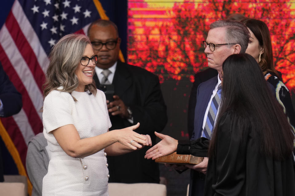 Arizona Democratic Gov. Katie Hobbs, left, smiles after taking the ceremonial oath of office during a public inauguration, shaking hands with U.S. Circuit Judge for the Ninth Circuit Court of Appeals Roopali Desai, right, as her husband, Patrick Goodman, second from right, looks on at the state Capitol in Phoenix, Thursday, Jan. 5, 2023. (AP Photo/Ross D. Franklin)