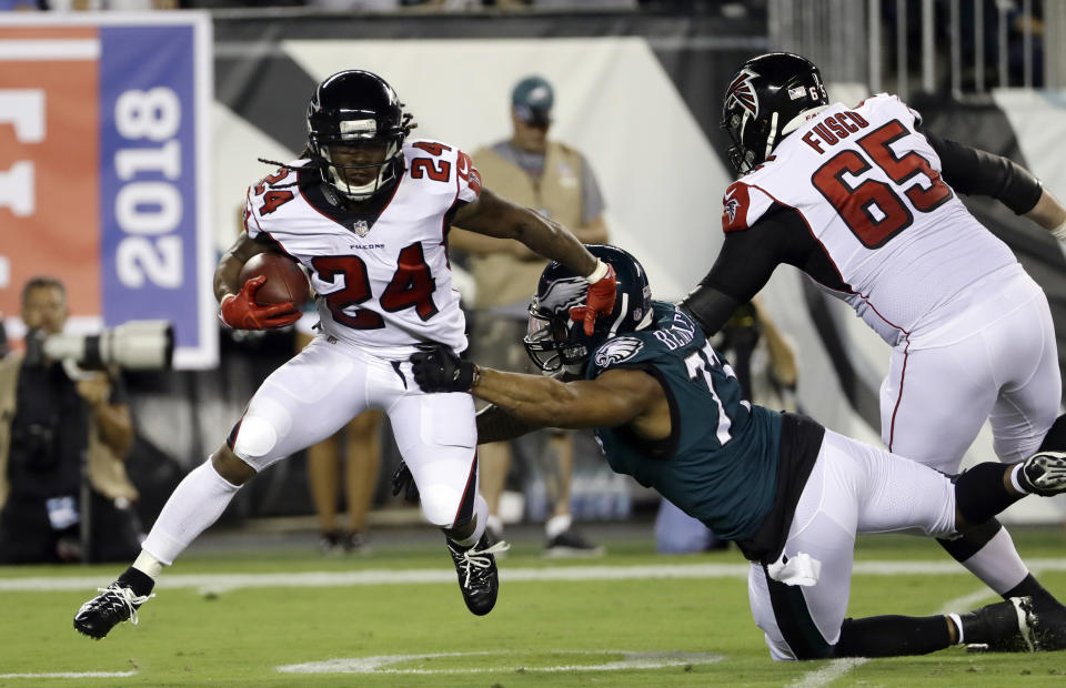 Atlanta Falcons' Devonta Freeman (24) tries to get away from Philadelphia Eagles' Michael Bennett (77) during the first half of an NFL football game Thursday, Sept. 6, 2018, in Philadelphia. (AP Photo/Michael Perez)