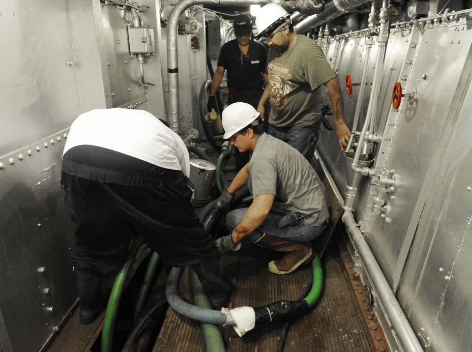 Men work to pump water from below the decks of the USS Texas Wednesday, June 13, 2012, in Houston. The 100-year-old battleship's hull sprung a leak five days ago and has been taking on as much as 1,000 gallons of seawater every minute as workers struggle to contain it. (AP Photo/Pat Sullivan)