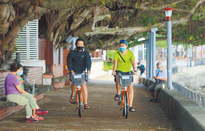 疫情指揮中心指揮官陳時中宣布，7月27日起全國疫情警戒從三級降為二級，室外放寬到100人，營業場所及公共場域人流控管或總量管制，室外空間至少每人1平方米為原則。圖為民眾23日騎Ubike逛淡水老街。（張鎧乙攝）