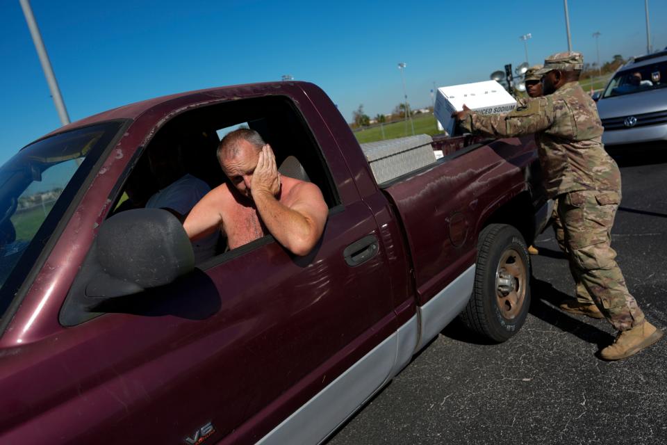 Members of the US Army National Guard load supplies into the back of a pick-up at a drive-through distribution point handing out food, water, and ice to local residents in need, three days after the passage of Hurricane Ian, in Fort Myers, Fla., Saturday, Oct. 1, 2022.