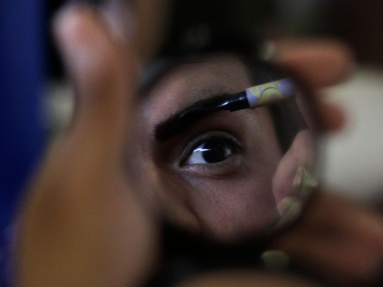 someone applying make up in a small mirror