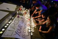 People light candles next to a banner reading "Europe, your hand is covered with blood" in front of the Eastern railway station in Budapest on August 28, 2015