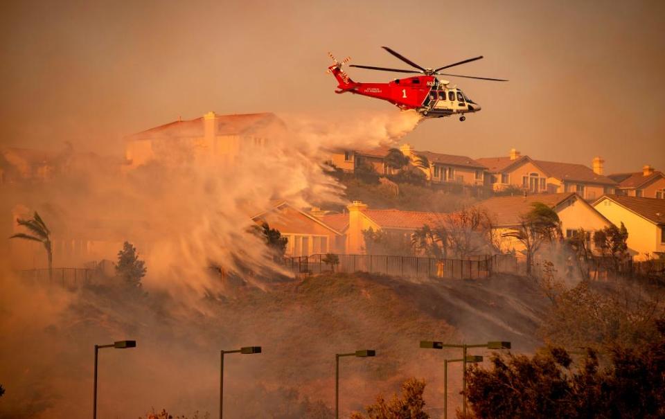 A helicopter makes a water drop to help fight the Saddleridge fire north of Los Angeles.
