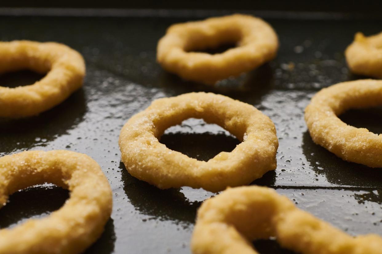 uncooked frozen onion rings on a baking tray.
