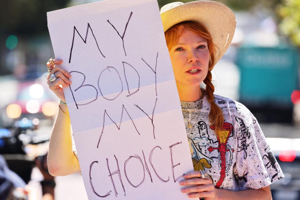 A woman holds a handwritten sign: "My Body My Choice."