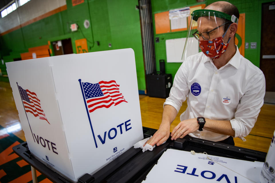 DETROIT, MI - AUGUST 4: Reuben Levy, volunteer, disinfect a voting booth after voters cast their ballots at a polling station inside Frederick Douglass Academy during Michigan Primary in Detroit, Michigan on Tuesday, August 4, 2020. (Photo by Salwan Georges/The Washington Post via Getty Images)