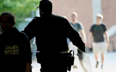 A University of North Carolina, Charlotte campus police officer carries a tactical shield after a shooting on Tuesday  - Credit: &nbsp;John Simmons/AP