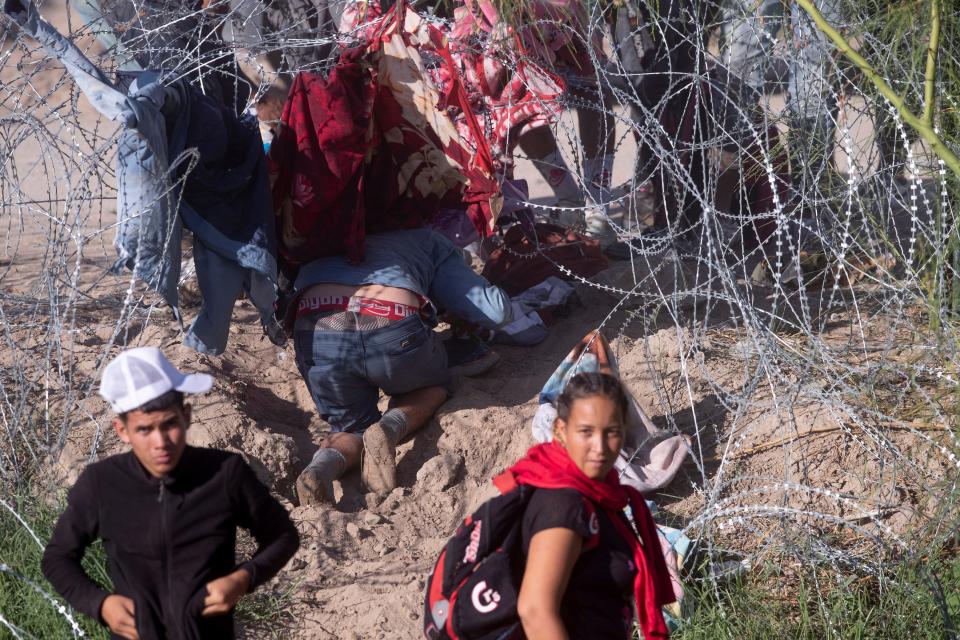 Migrants breach concertina wire set by the Texas National Guard at the border between Juárez and El Paso on Sept. 20.