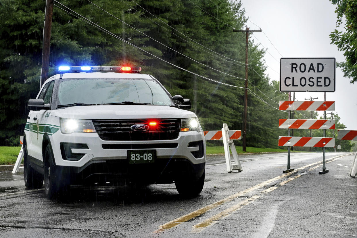 Stonebridge Crossing Road is closed near near Houghs Creek in Upper Makefield, Pa., Sunday morning, July 16, 2023, following fatal flash flooding on Saturday. Several people were killed when torrential rains in area cause fast rising floodwaters washing away cars (Tom Gralish/The Philadelphia Inquirer via AP)