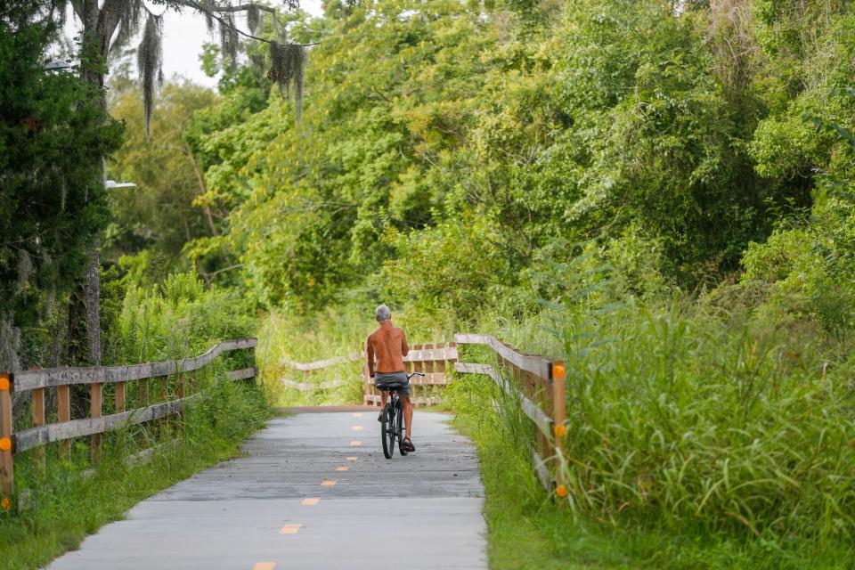 A bicycle rider takes the Truman Linear Park Trail toward Lake Mayer.