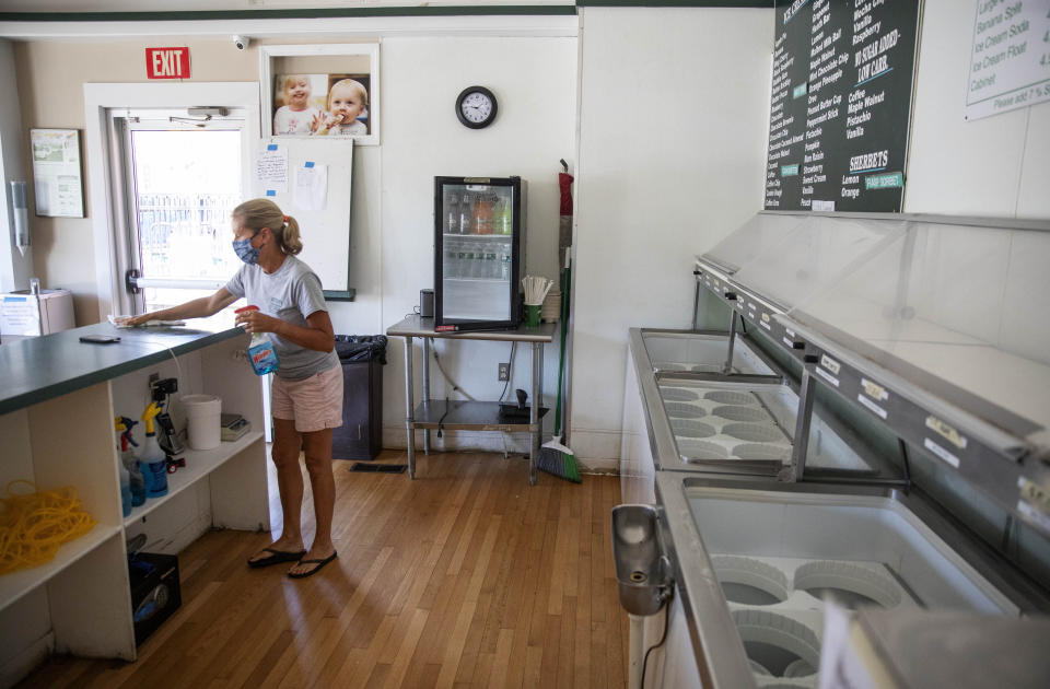 Chris Brophy cleans one of two Brickley's Ice Cream shops she owns with her husband which they closed for the season after teenage workers were harassed by customers who refused to wear a mask or socially distance, in Wakefield, R.I., Wednesday, July 29, 2020. Disputes over masks and mask mandates are playing out at businesses, on public transportation and in public places across America and other nations. (AP Photo/David Goldman)