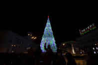 FILE - In this Thursday, Nov. 26, 2020 file photo, a man waves at his camera phone during the switching-on of traditional Christmas lights in Madrid, Spain. People are waiting to see what restrictions will be in place over Christmas and the New Year as Spanish regions are continuing to adjust their various limitations against the coronavirus pandemic. (AP Photo/Paul White, File)