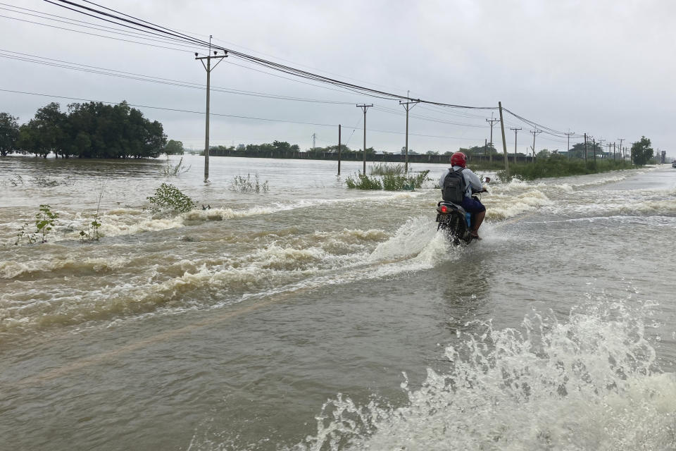 A local resident drives motorbike on a flooded road in Bago, about 80 kilometers (50 miles) northeast of Yangon, Myanmar, Monday, Oct. 9, 2023. Flooding triggered by heavy monsoon rains in Myanmar’s southern areas has displaced more than 10,000 people and disrupted traffic on the rail lines that connect the country’s biggest cities, officials and state-run media said Monday. (AP Photo/Thein Zaw)