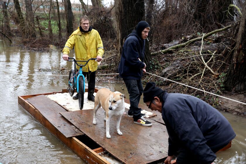 SACRAMENTO, CA - JANUARY 05: David Toney (cq), 60, far left, who is homeless, uses a raft to get off a flooded homeless encampment on Bannon Island, along the Sacramento River on Thursday, Jan. 5, 2023 in Sacramento, CA. Toney, originally of Indianapolis, Indiana, has been homeless in the area for 15 years and lived on the island for 10 years. David had to leave the island and share a tent with his partner. The storms last week caused flooding on the island, around 60 people who live in the encampment have being warned to move to higher ground. Massive 'atmospheric river' to bring heavy rains, winds, flooding across California. Residents, business owners and emergency workers nervously await the epic 'Bomb cyclone' storm expected to slam the Bay Area Wednesday and Thursday. Urgent high wind warning starting at 4 a.m. Wednesday, with gusts up to 50 mph in low-lying areas and up to 70 mph at the coast and among the region's highest peaks. (Gary Coronado / Los Angeles Times)
