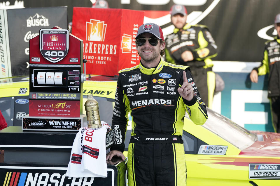 Ryan Blaney stands next to the winner's trophy after the NASCAR Cup Series auto race at Michigan International Speedway, Sunday, Aug. 22, 2021, in Brooklyn, Mich. (AP Photo/Carlos Osorio)