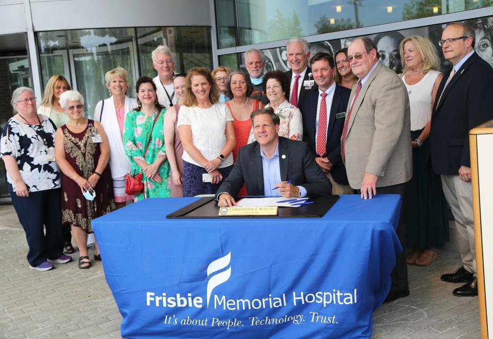 Gov. Chris Sununu is surrounded by health-care leaders and lawmakers outside Frisbie Memorial Hospital in Rochester Friday, July 22, 2022. He signed into law a bill designed to be the start of a health-care facility workplace violence prevention program.