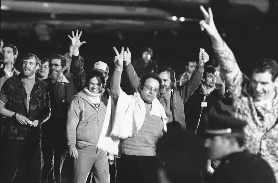 FILE - A group of unidentified American hostages give the victory sign as they emerge from an aircraft in Algiers on Jan. 21, 1981 after their flight from Teheran, where they had been held captive for 444 days in Iran. Caulkin, a retired Associated Press photographer has died. He was 77 and suffered from cancer. Known for being in the right place at the right time with the right lens, the London-based Caulkin covered everything from the conflict in Northern Ireland to the Rolling Stones and Britain’s royal family during a career that spanned four decades. (AP Photo/Dave Caulkin, File)