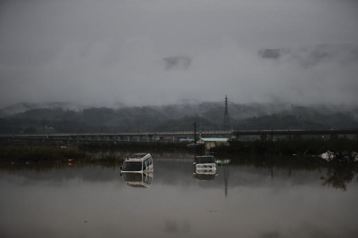 Two vehicles are submerged in floodwaters Monday, Oct. 14, 2019, in Hoyasu, Japan. Rescue crews in Japan dug through mudslides and searched near swollen rivers Monday as they looked for those missing from a typhoon that left as many as 36 dead and caused serious damage in central and northern Japan. (AP Photo/Jae C. Hong)