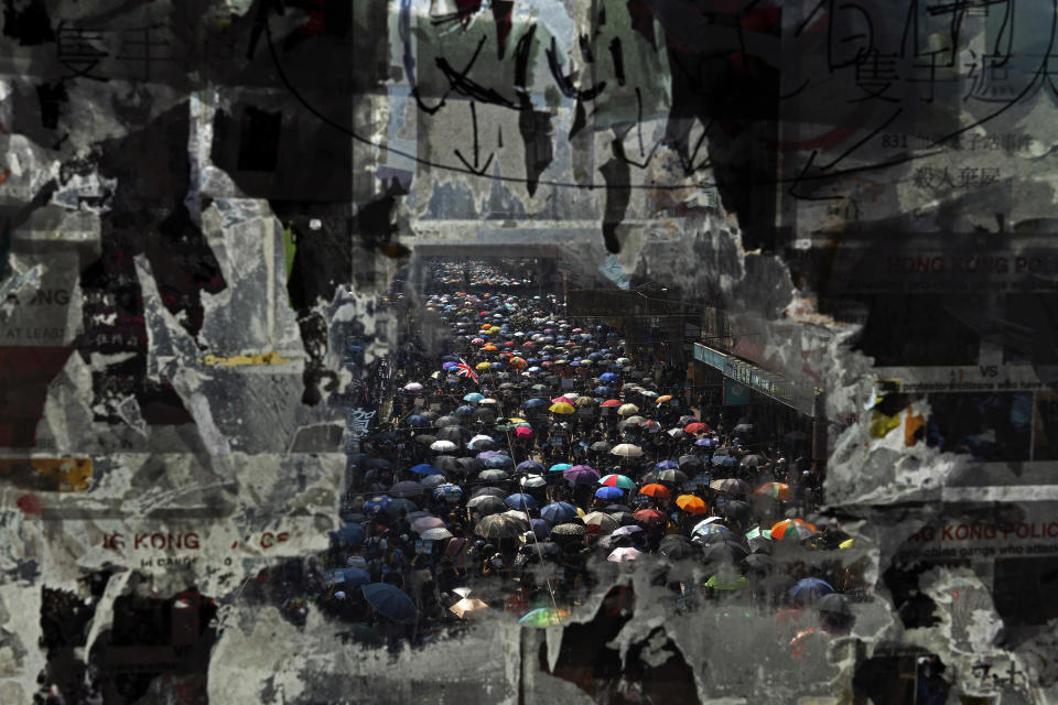 FILE - In this Oct. 1, 2019, file photo, marching anti-government protesters are seen through a glass with peeled off posters in Hong Kong. With Britain the latest country to scrap an extradition treaty with Hong Kong, the focus has returned to concerns over Chinese justice that sparked months of anti-government protests in the semi-autonomous city last year. (AP Photo/Vincent Yu, File)