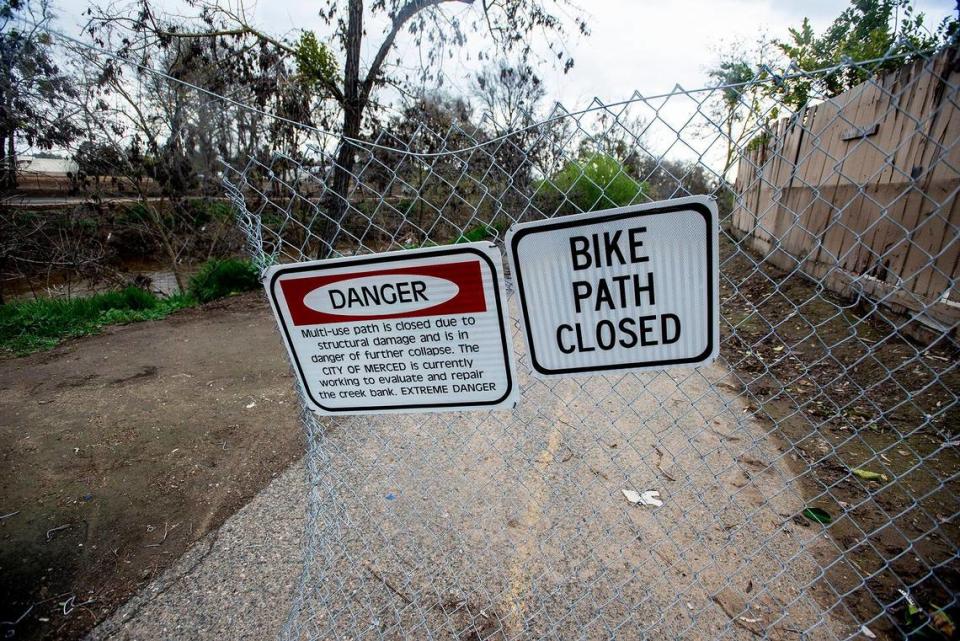 Signs warn pedestrians of a dangerous section of bike path along Bear Creek near West 25th Street in Merced, Calif., on Tuesday, March 14, 2023.