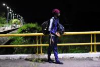 A migrant waits for the fellow migrants as they walk along a road in a caravan towards the United States, in Tapachula