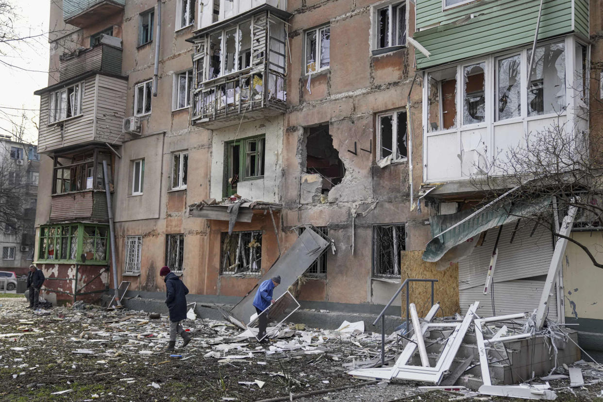 People walk next to an apartment building heavily damaged by shelling in Mariupol. 