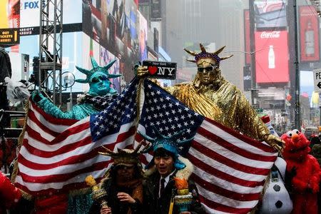 People dressed up as Statues of Liberty pose for pictures at Times Square during a snowfall, as a cold weather front hits the region, in Manhattan, New York, U.S., December 30, 2017. REUTERS/Eduardo Munoz