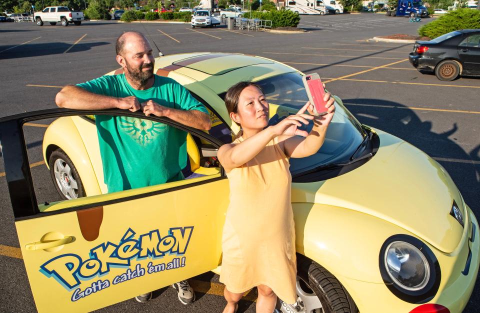 From left, fans, AJ and Amy Peacock take a picture with the Volkswagen Bug that has been customized as a Pokémon car that talks and sings in Camden, Monday, July 10, 2023.