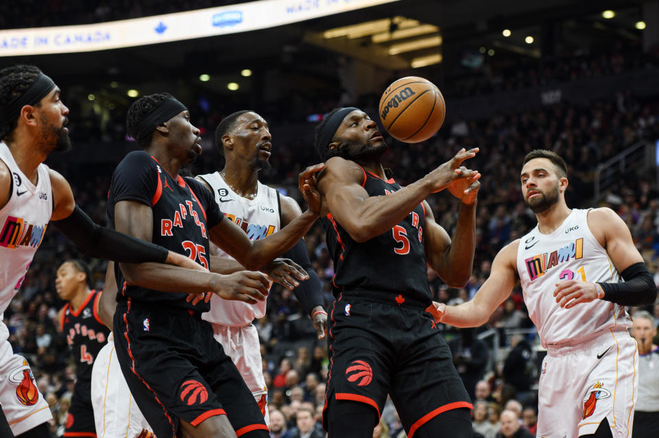 Toronto Raptors forward Precious Achiuwa (5) and forward Chris Boucher (25) look to recover a loose ball while defended by Miami Heat guard Max Strus (31), center Bam Adebayo (13) and guard Gabe Vincent (2) during the first half of an NBA basketball game in Toronto on Tuesday, March 28, 2023. (Christopher Katsarov/The Canadian Press via AP)