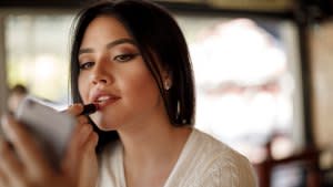 Young woman applying lipstick at a cafe