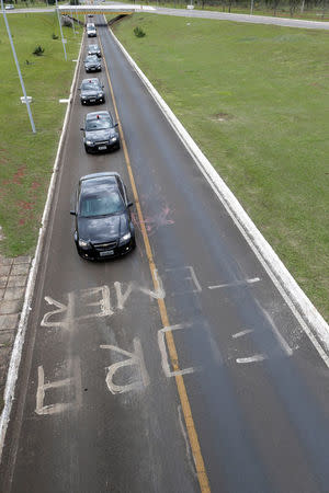 The motorcade of Brazilian President Michel Temer drives past graffiti which reads 'Out with Temer' in Brasilia, Brazil May 19, 2017. REUTERS/Ueslei Marcelino