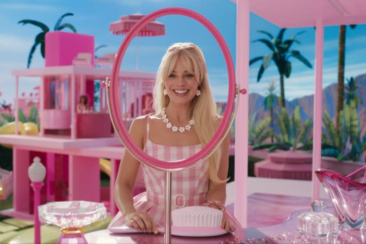 Margot Robbie looks through a mirrorless mirror in Barbie.